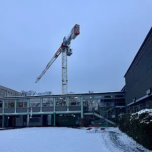 Blick auf unsere Schule an einem Wintermorgen. Dahinter sieht man den Kran, der gerade unseren Neubau errichtet.